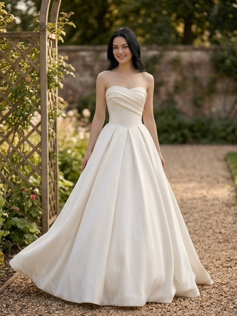 Lacey Bridal Ltd. ALESSIA strapless satin ballgown with a pleated bodice and voluminous skirt in a garden setting.