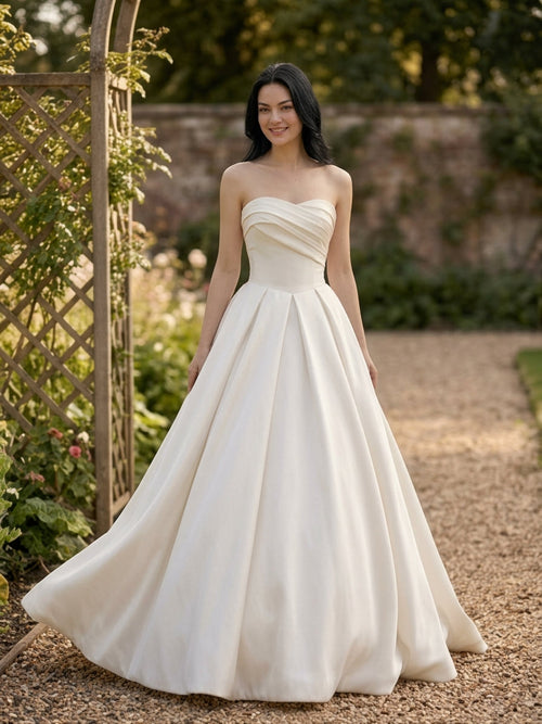 Lacey Bridal Ltd. ALESSIA strapless satin ballgown with a pleated bodice and voluminous skirt in a garden setting.
