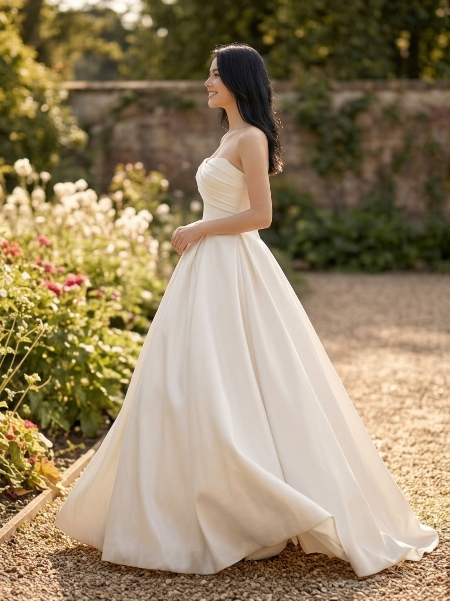 Lacey Bridal Ltd. ALESSIA strapless satin ballgown with pleated bodice and voluminous skirt in a garden setting
