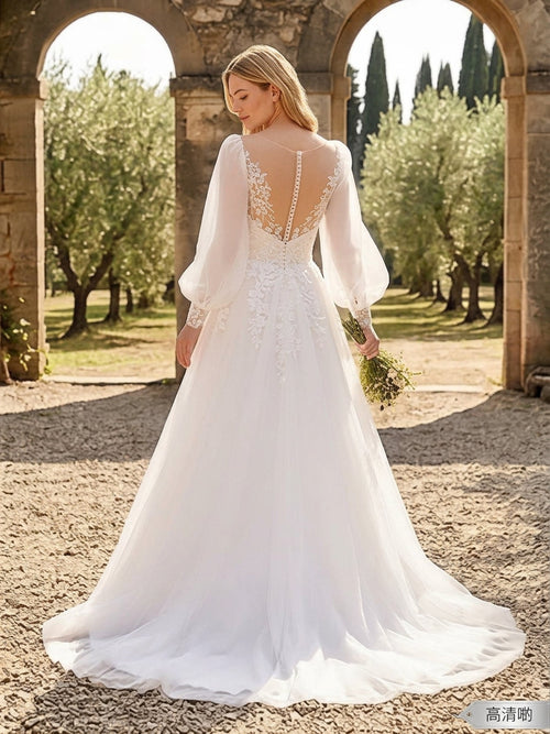 Lacey Bridal Ltd. Anthea A-line wedding gown with illusion back, balloon sleeves, and lace appliqué in an olive grove.