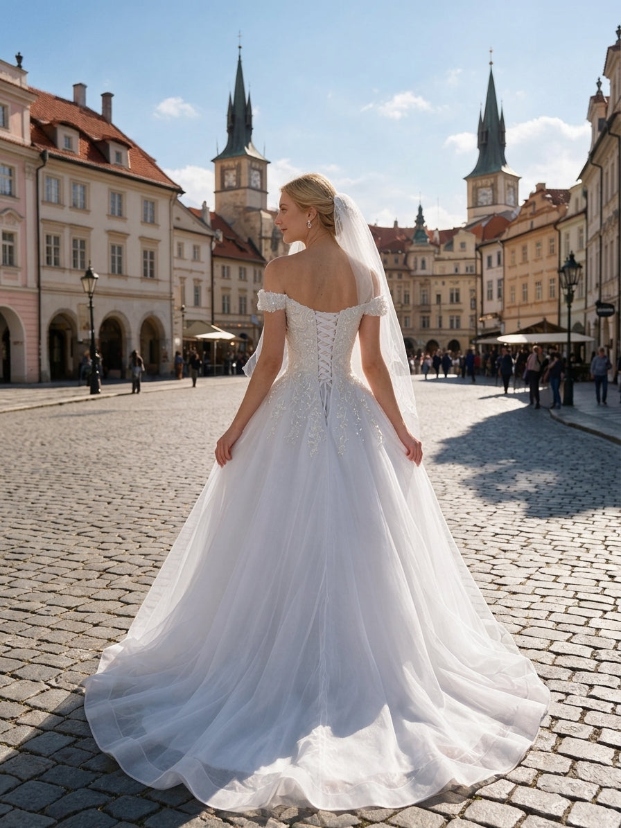 Lacey Bridal Ltd. Athena off-the-shoulder A-line wedding gown with lace corset back and tulle skirt in a city square.