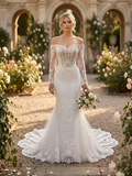 Lacey Bridal Ltd. Augusta off-the-shoulder lace wedding gown with corset bodice and chapel train in a garden setting.
