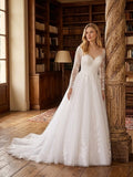 Lacey Bridal Ltd. BIANCA A-line wedding gown with long illusion lace sleeves and a full tulle skirt in a library.