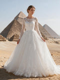 Lacey Bridal Ltd. Callista A-line wedding gown with long lace sleeves and floral tulle skirt in a desert setting.