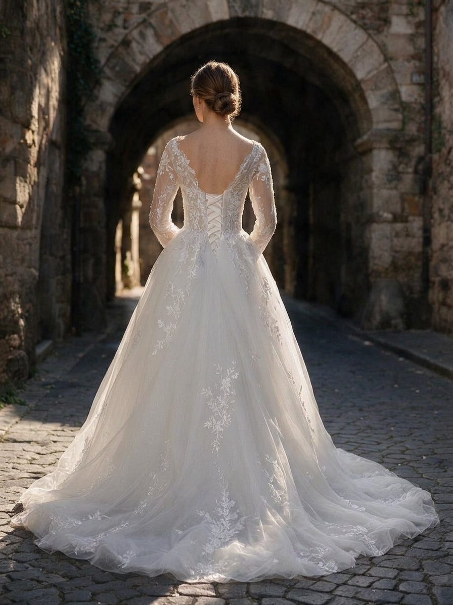 Lacey Bridal Ltd. Cassandra A-line wedding gown with long illusion sleeves, lace-up corset back, and tulle train.