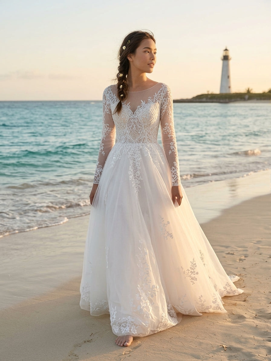 Lacey Bridal Ltd. Clementine A-line wedding gown with floral lace, illusion sleeves, and tulle skirt on a beach.