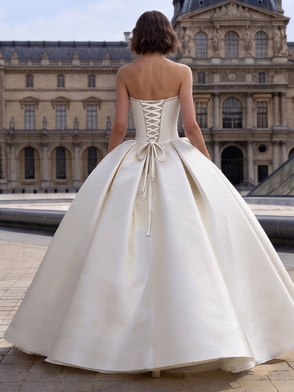 Lacey Bridal Ltd. Delia strapless satin ball gown with a corset lace-up back and voluminous skirt in a Parisian setting