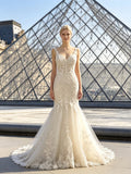 Lacey Bridal Ltd. ivory mermaid wedding gown with lace appliqués, beadwork, and a chapel train in front of the Louvre.