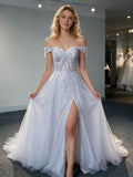 Lacey Bridal Ltd. Elysian A-line wedding dress with off-shoulder neckline, botanical lace, and tulle skirt with slit.