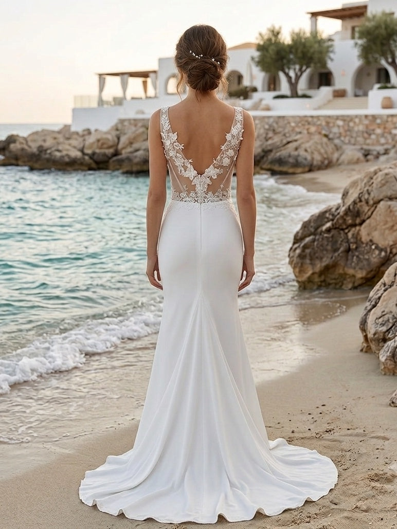 Lacey Bridal Ltd. FLORA crepe sheath wedding gown with illusion lace back and 3D floral appliqués on a coastal beach.