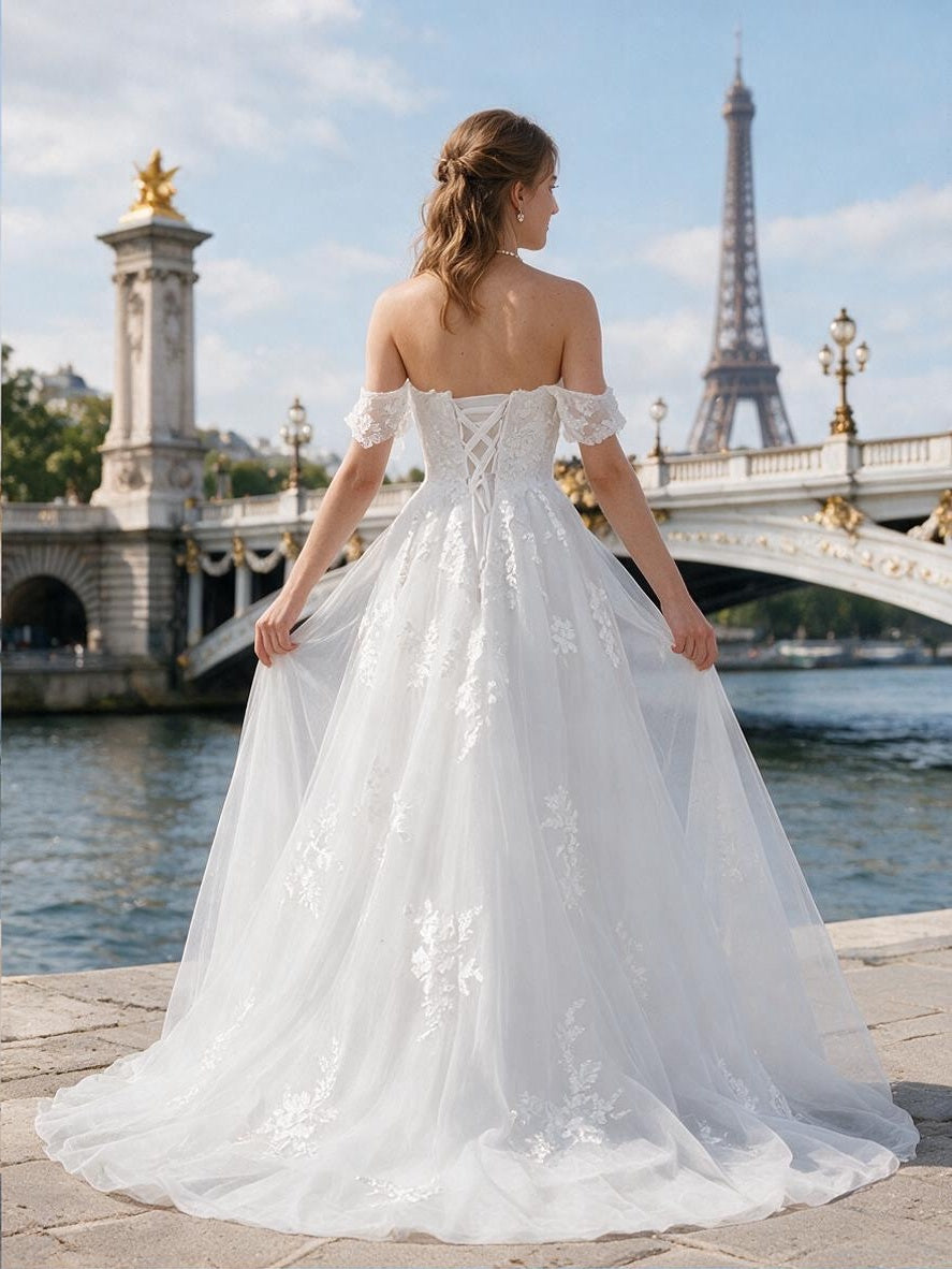 Lacey Bridal Ltd. GISELLE A-line wedding dress with off-the-shoulder lace straps and corset back in front of Eiffel Tower