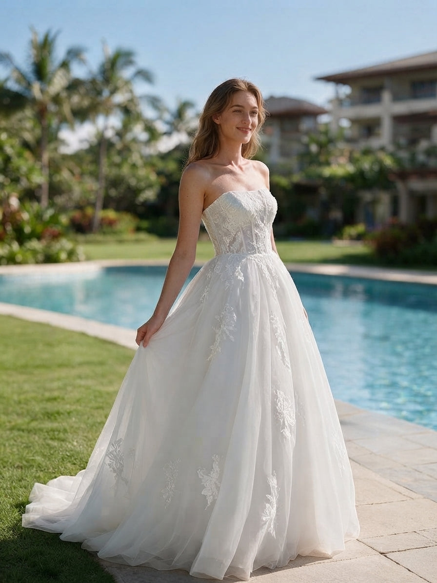Lacey Bridal Ltd. Henrietta strapless A-line wedding gown with floral lace embroidery and tulle skirt by a pool.