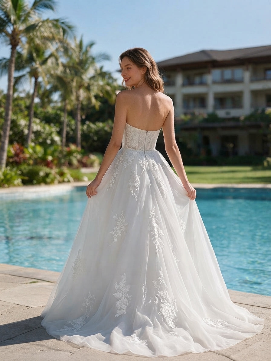 Lacey Bridal Ltd. Henrietta strapless A-line wedding gown with floral lace embroidery and tulle skirt by a pool.