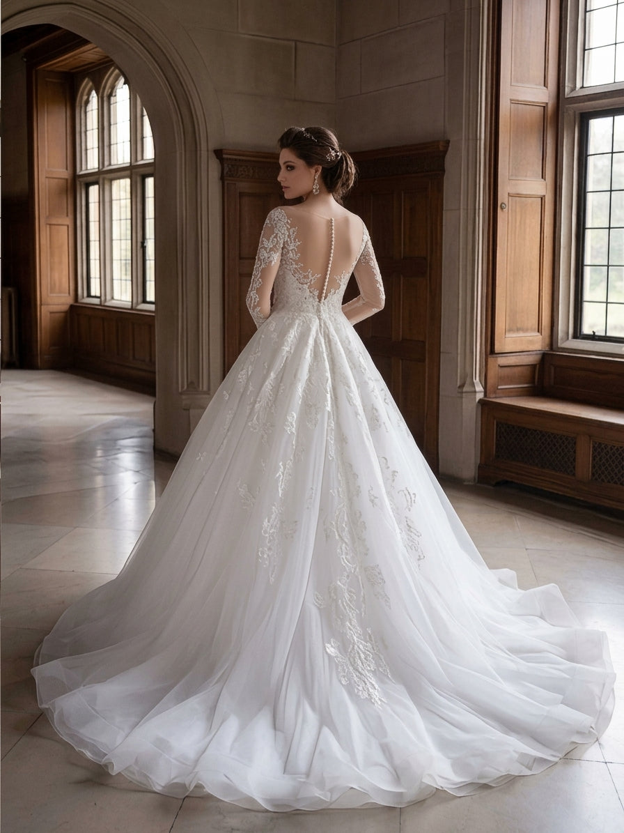 Lacey Bridal Ltd. Imogen ball gown with illusion back, long lace sleeves, and full tulle skirt with a cathedral train.