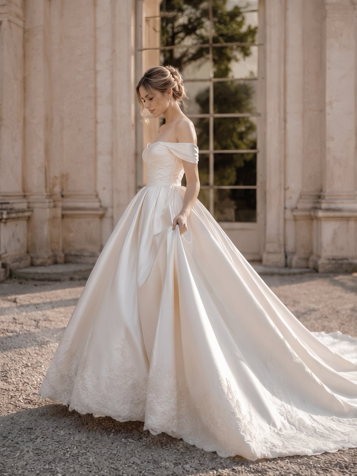 Lacey Bridal Ltd. JOVIENNE satin ball gown with off-the-shoulder neckline, ruched bodice, and beaded lace hem detail.