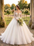 Lacey Bridal Ltd. LAURENTINE ball gown with illusion sleeves, beaded lace bodice, and full tulle skirt in a garden.