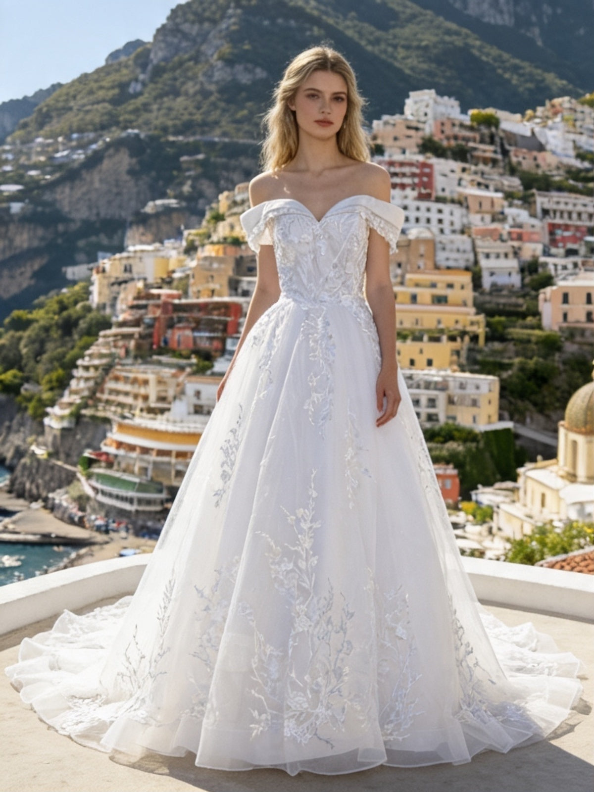 Lacey Bridal Ltd. MARINA off-the-shoulder ballgown with vine embroidery and tulle skirt on a coastal terrace.