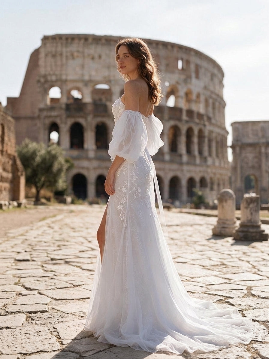 Lacey Bridal Ltd. PRIMROSE A-line wedding dress with puff sleeves, 3D floral lace, and thigh slit in front of Colosseum