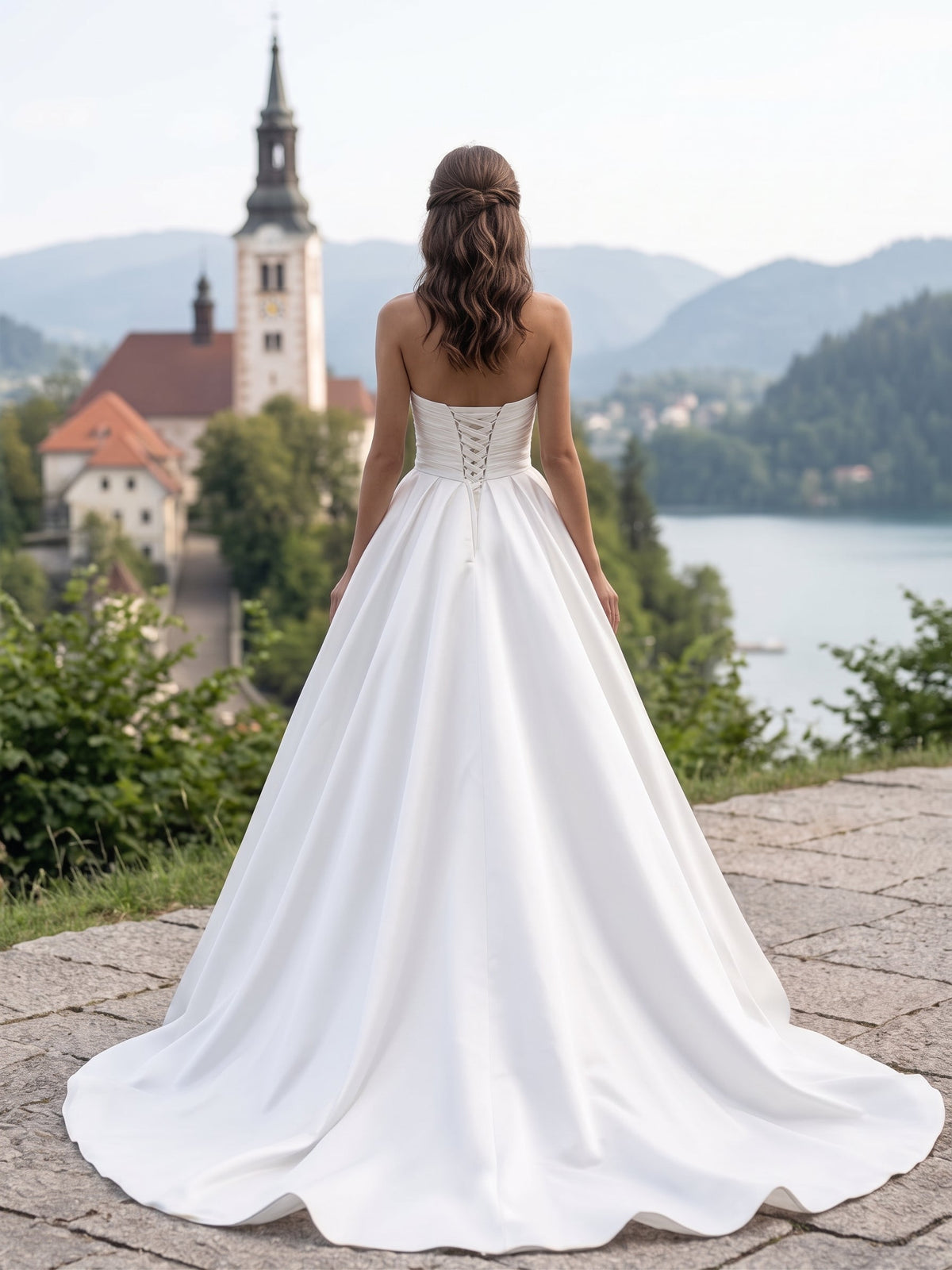 Lacey Bridal Ltd. Romilly satin ball gown with corset back and flowing train, worn by a bride overlooking a lake.