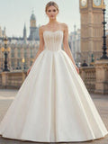 Lacey Bridal Ltd. SOLENE strapless ivory satin ballgown with pearl-encrusted corset bodice and full pleated skirt.