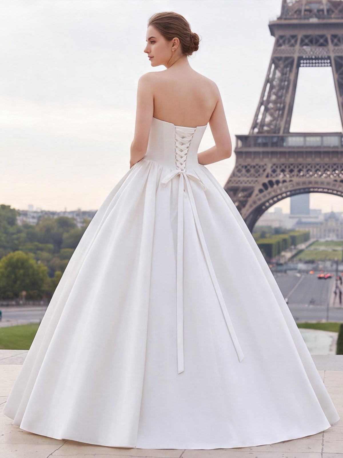 Lacey Bridal Ltd. strapless white satin ballgown with a lace-up corset back and sweeping train in front of Eiffel Tower