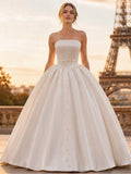 Lacey Bridal Ltd. LUCIENNE strapless satin ballgown with a pleated corset bodice and button-front voluminous skirt.