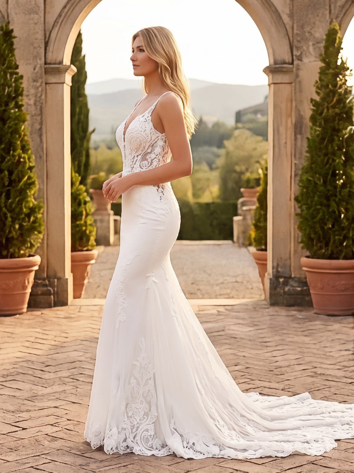 Lacey Bridal Ltd. Titania mermaid wedding gown with lace bodice, plunging neckline, and tulle train in a garden setting