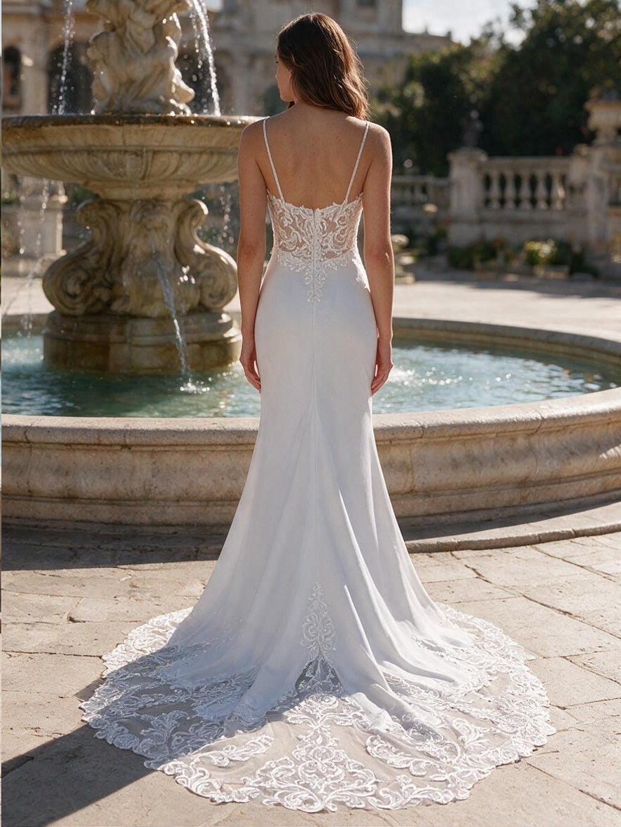 Lacey Bridal Ltd. Verena ivory mermaid wedding gown with a sheer lace back, spaghetti straps, and a lace-trimmed train.